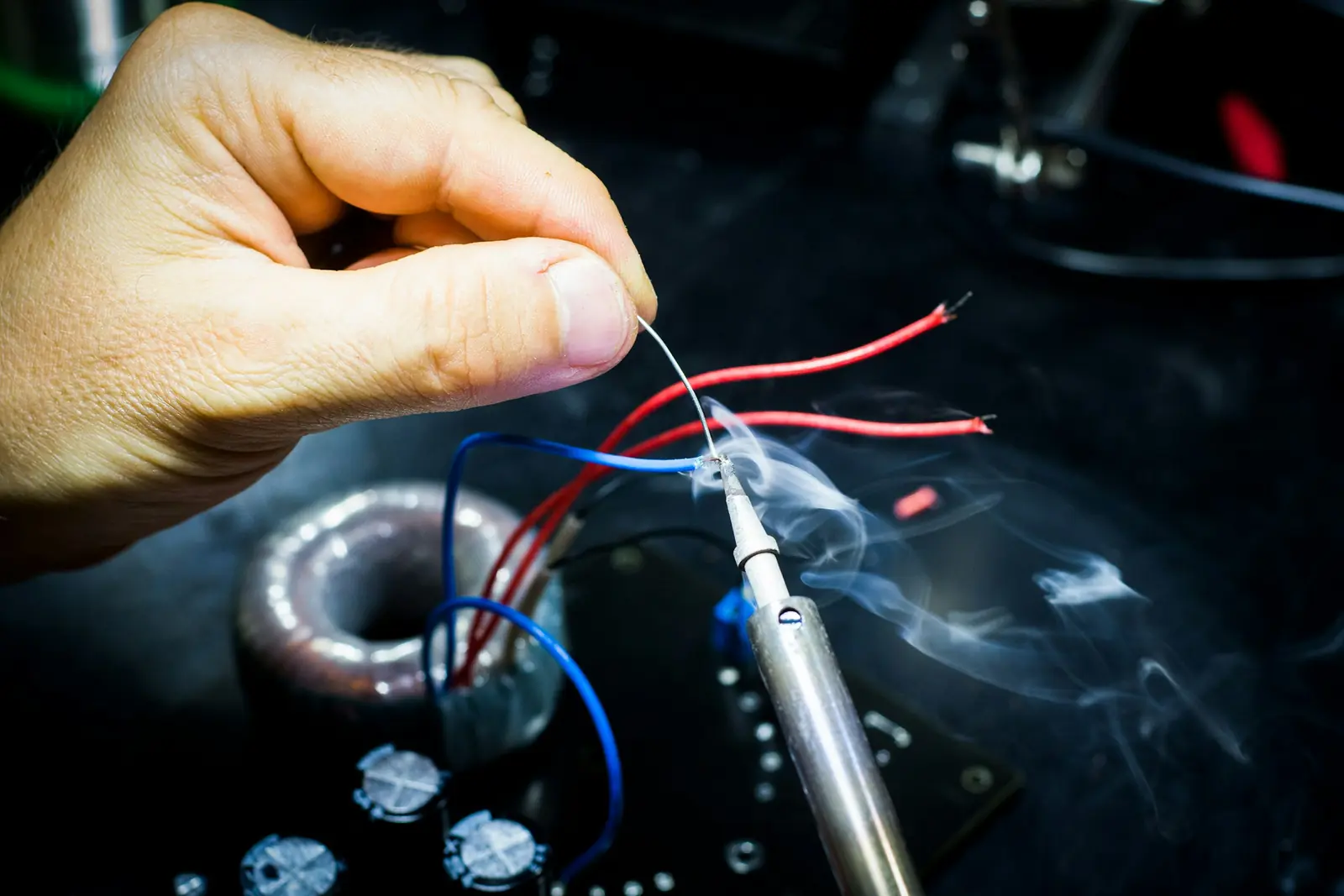 A hand soldering wires on a circuit board