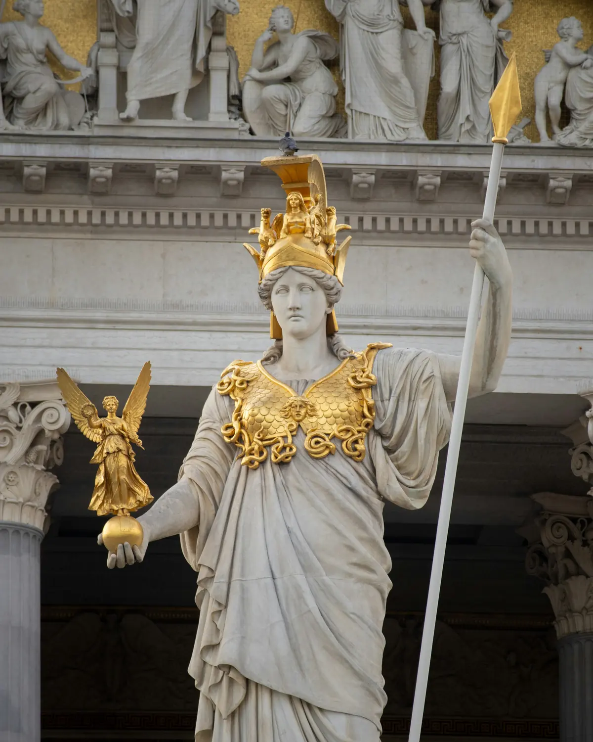Marble statue of Athena with a gold helmet, holding a spear and a small winged figure