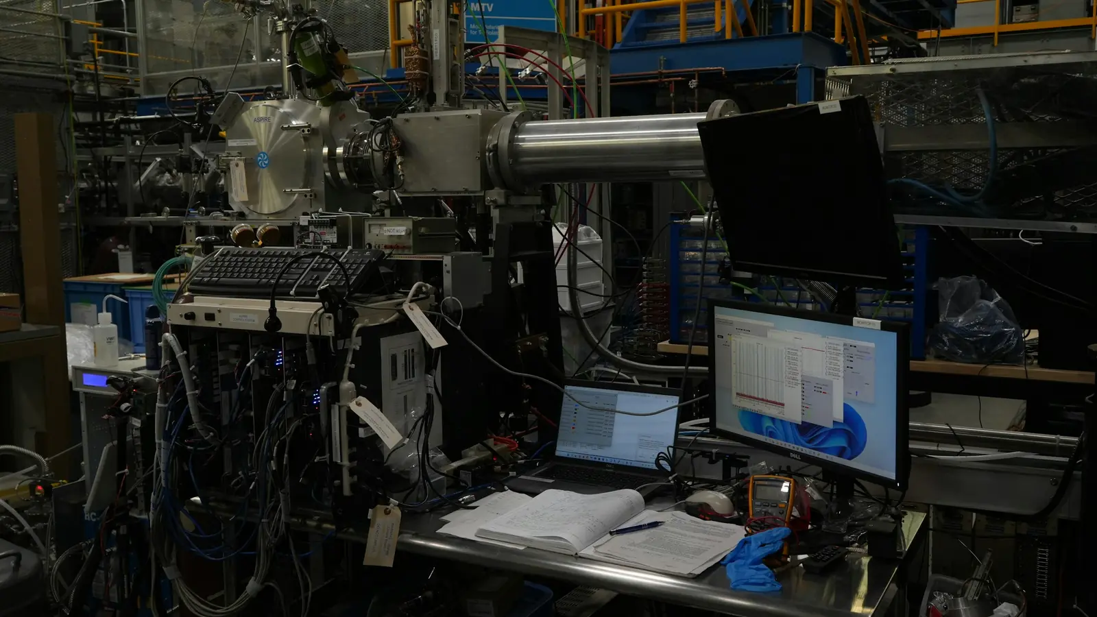 A research lab bench crowded with instruments, cables, and computer screens