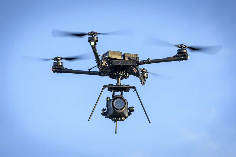 A heavy-lift drone in flight, with a large sensor pod below it