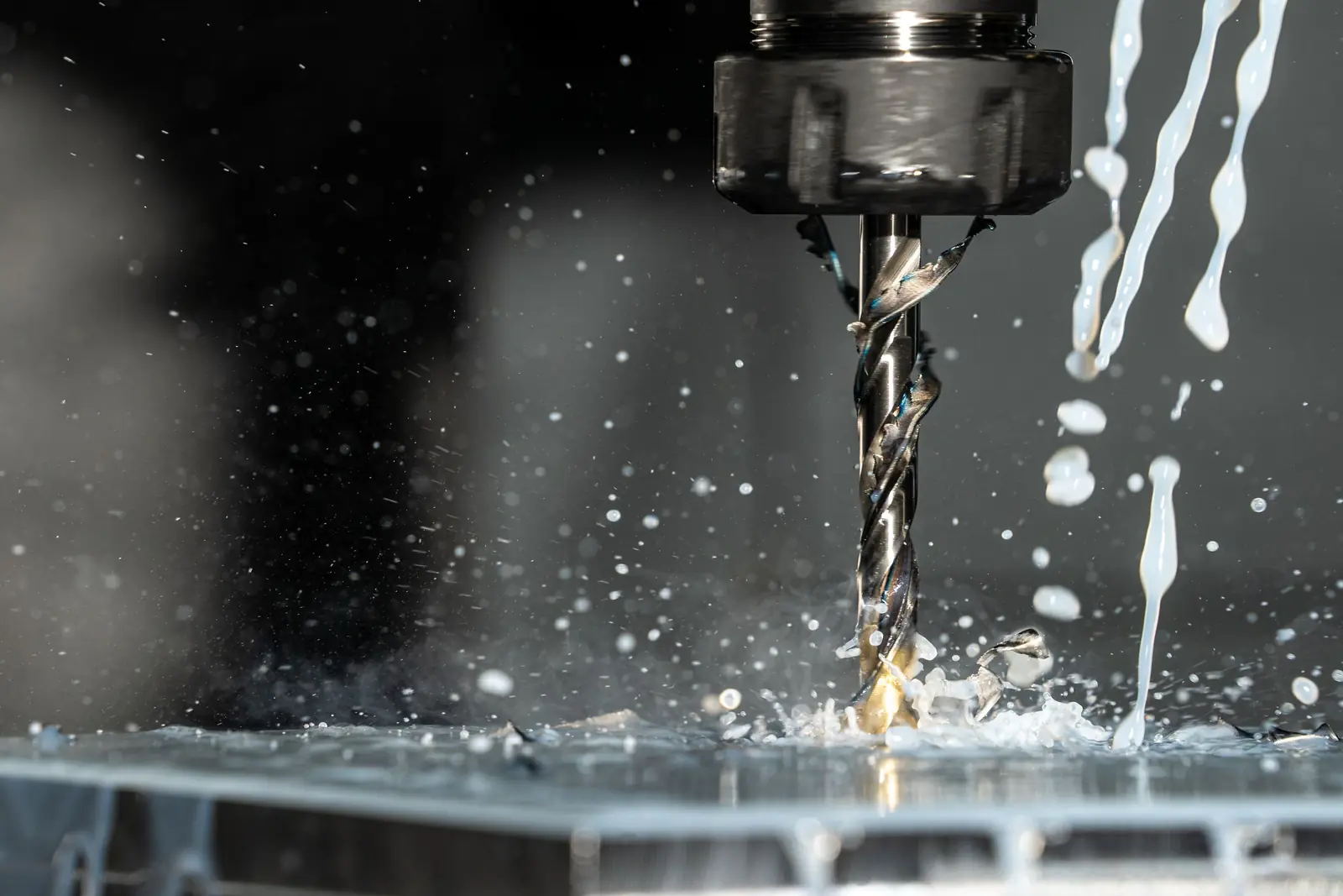 A drill cutting metal with coolant splashing