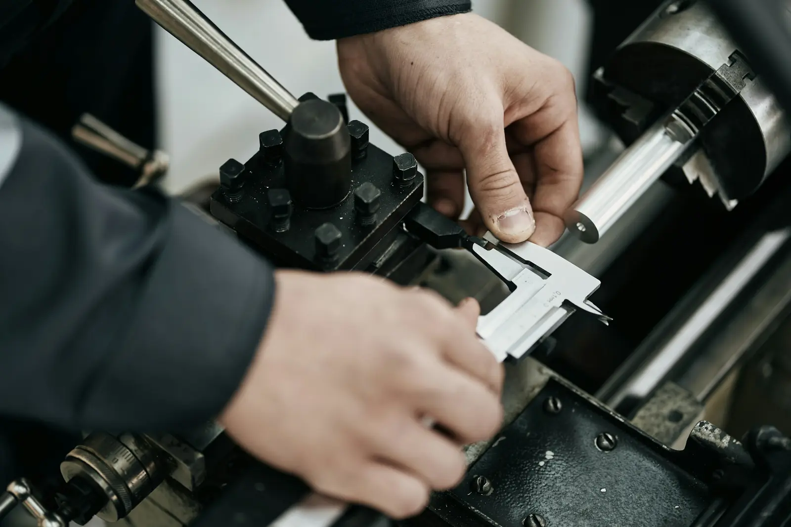 Hands measuring a part with a caliper