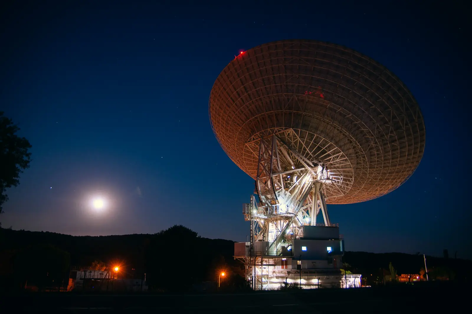 A large radio dish lit up at night